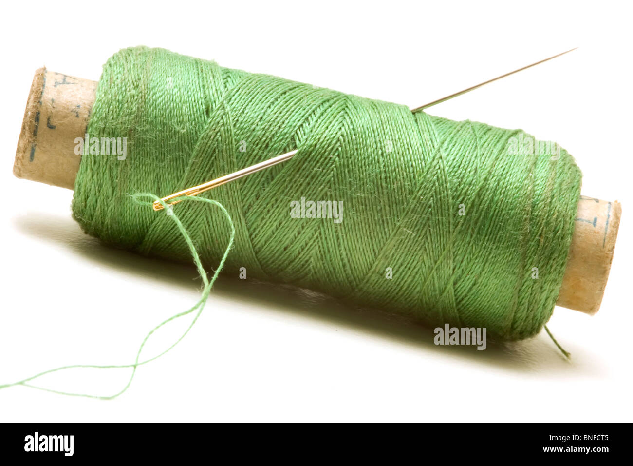 Spool of green thread and needle Stock Photo