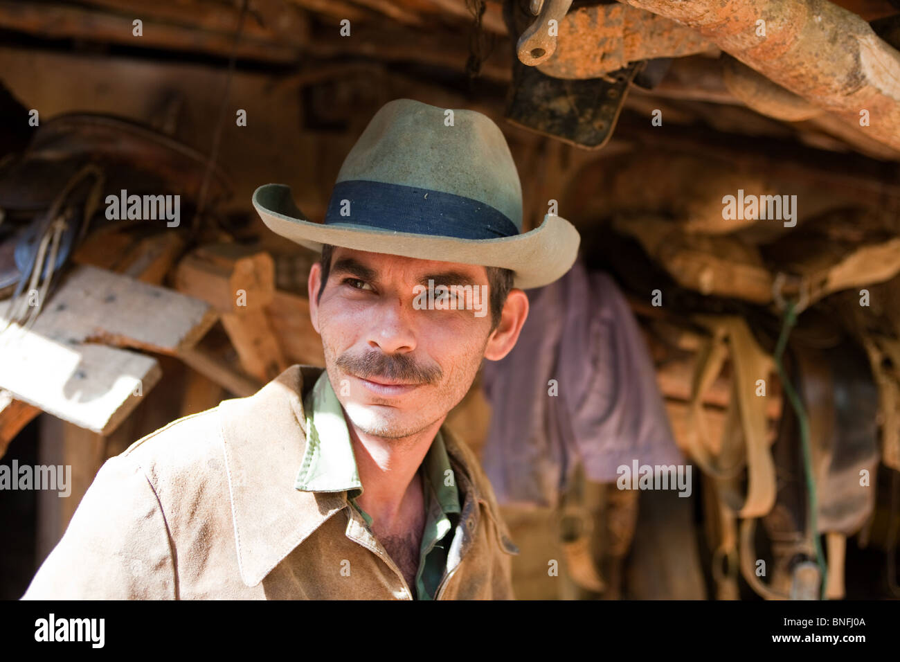 A rancher standing in front of saddles outside his home in a ...