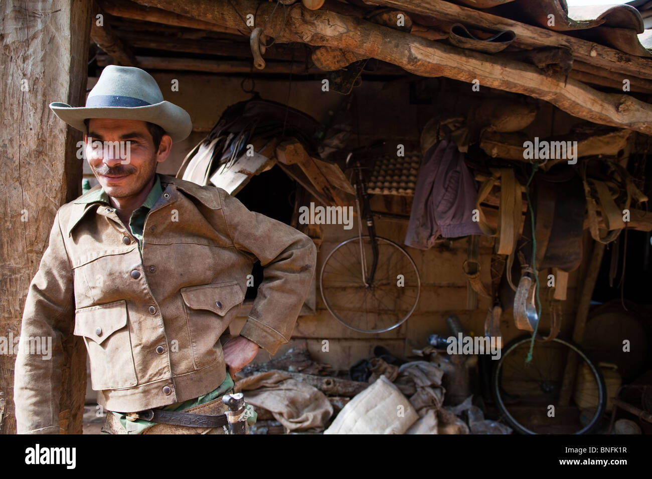 A rancher standing in front of saddles outside his home in a ...