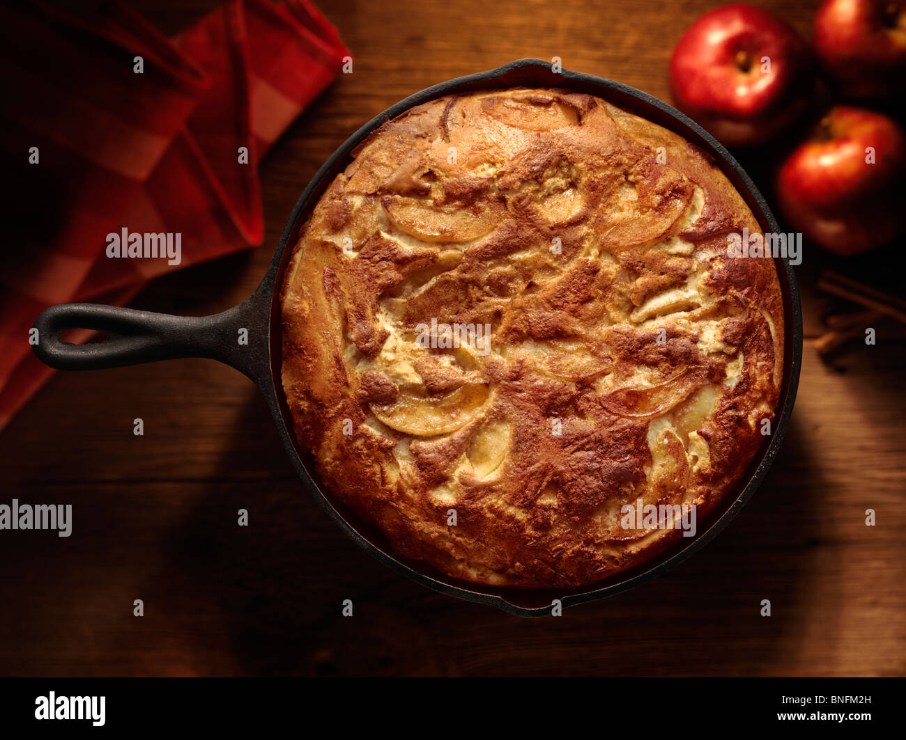 Apple pancake in cast iron pan hot from the oven on rough cut wood with