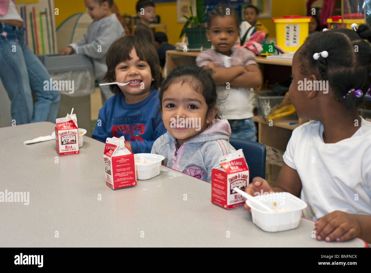 4 year old preschool children eating cereal for breakfast at school