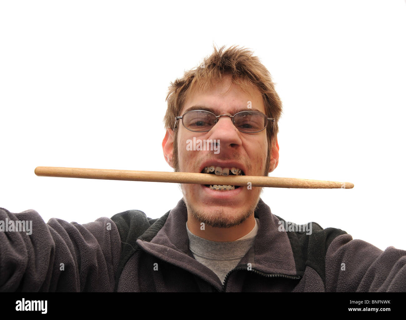 Drummer biting his drumstick with braces on white background Stock