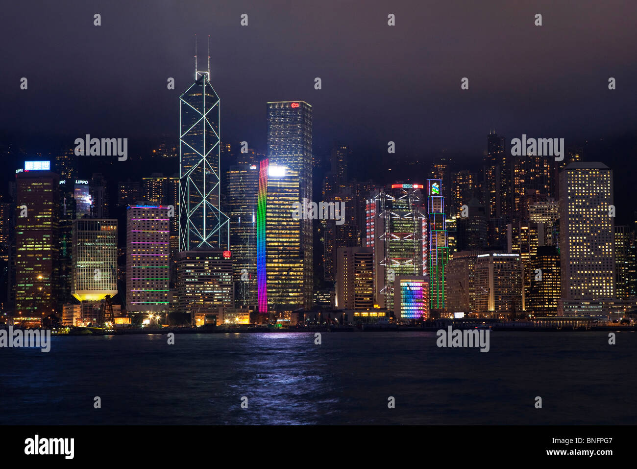 Tall buildings on Hong Kong Island city centre as seen across the harbour from Tsim Sha Tsui on Kowloon side at night Stock Photo