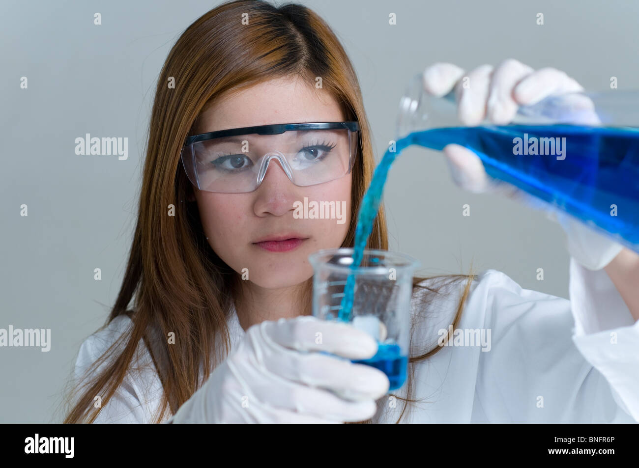 Scientist pouring chemicals in a laboratory Stock Photo