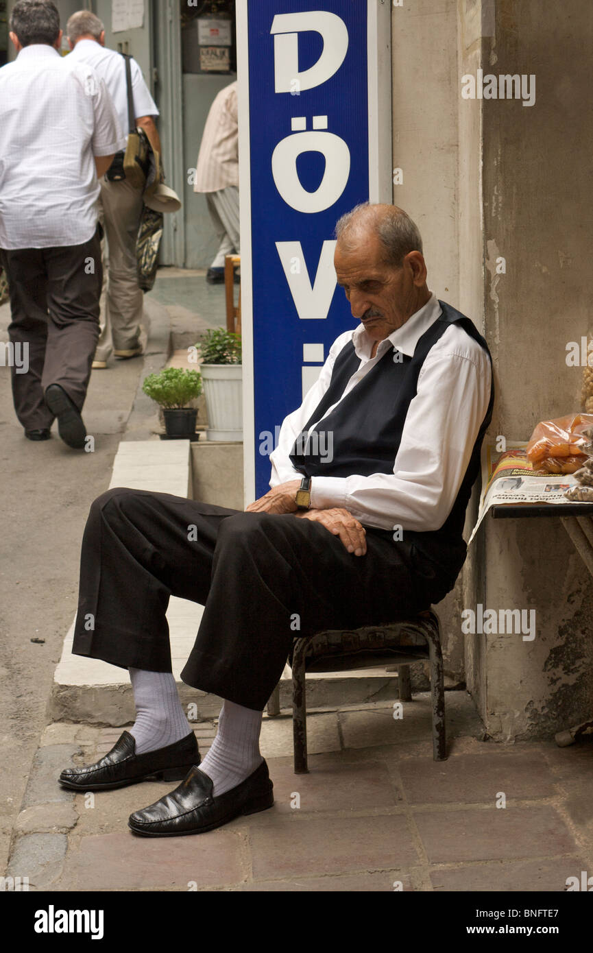 An smartly dressed old man has a nap outside his shop on the edge of the Grand Bazaar (Kapali Carsi), completed in 1660 Stock Photo