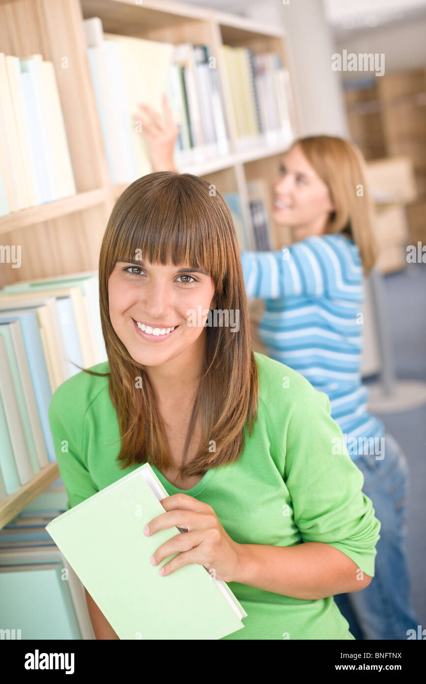 Student in library two woman hold book from bookshelf Stock Photo Alamy