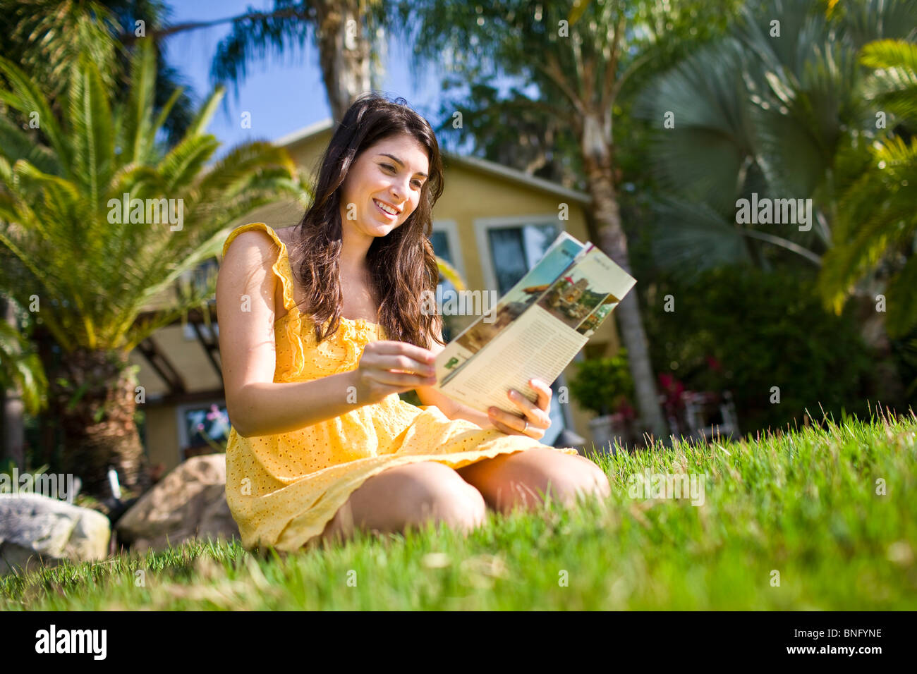 Young woman reading a magazine in a lawn Stock Photo