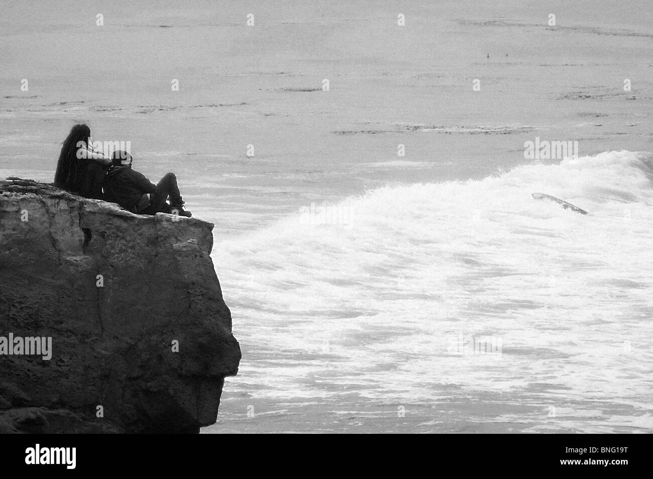 Couple sitting on a cliff, Steamer Lane, Santa Cruz, California, USA