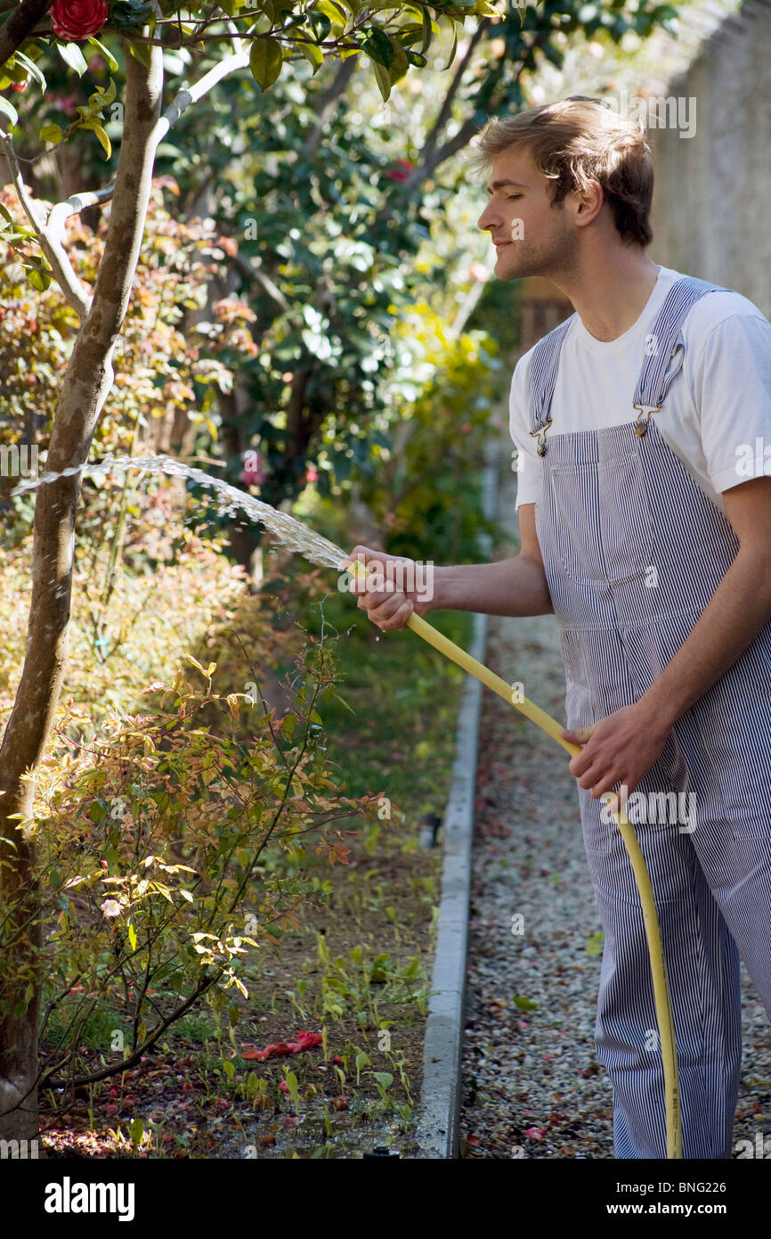 young man watering with hosepipe Stock Photo
