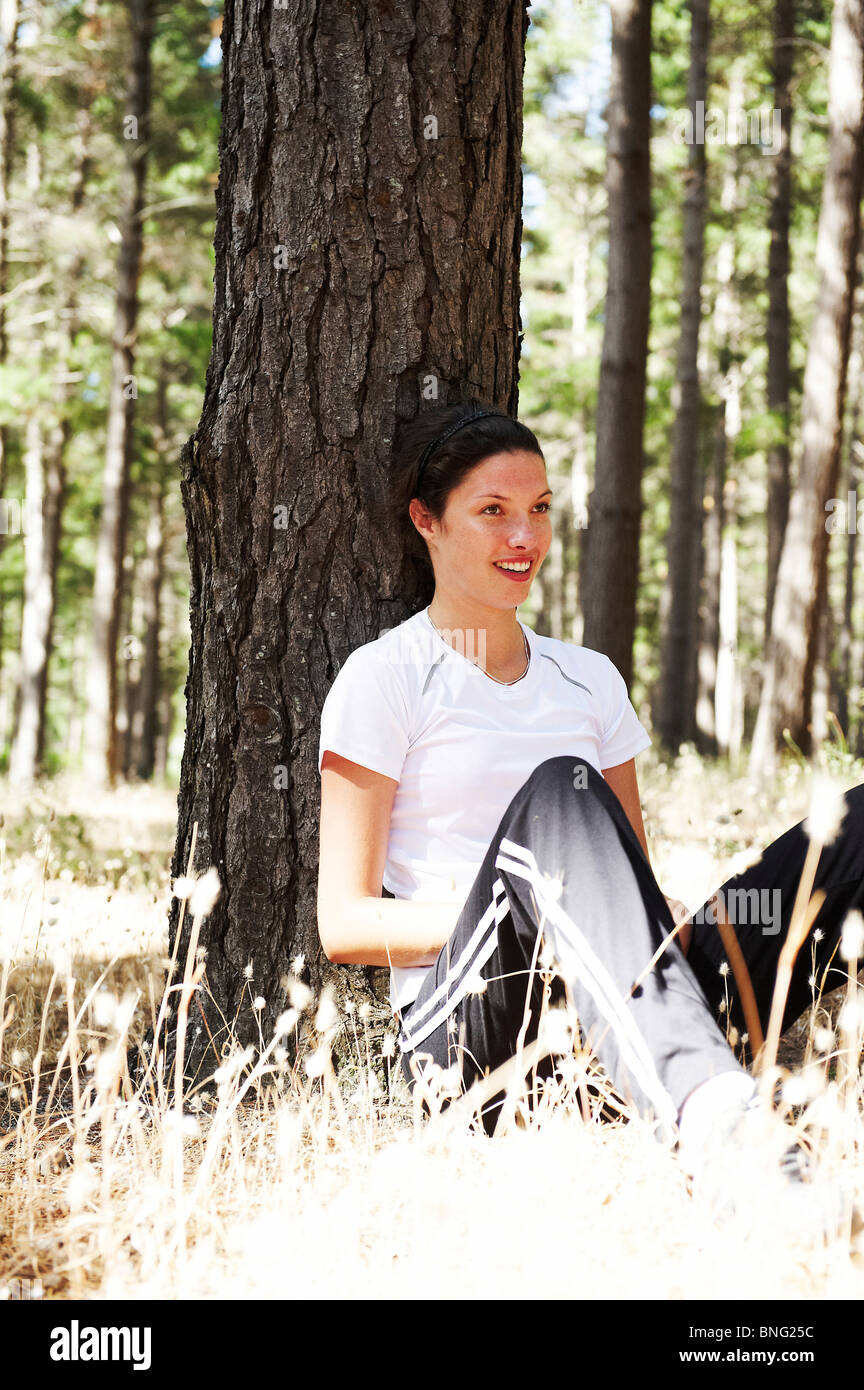 Young woman resting after jogging in a forest Stock Photo - Alamy