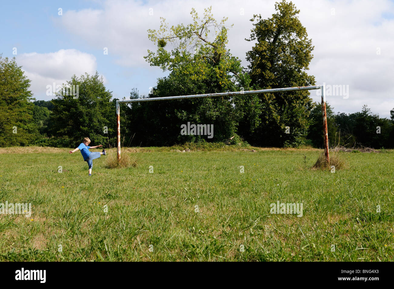 Stock photo of a 10 year old boy pretending to be playing football on an old football field. Stock Photo