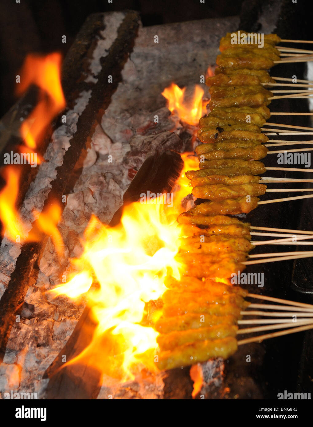 Satay chicken on skewers being cooked with an open flame at Lau Pa Sat hawker stalls in Singapore Stock Photo