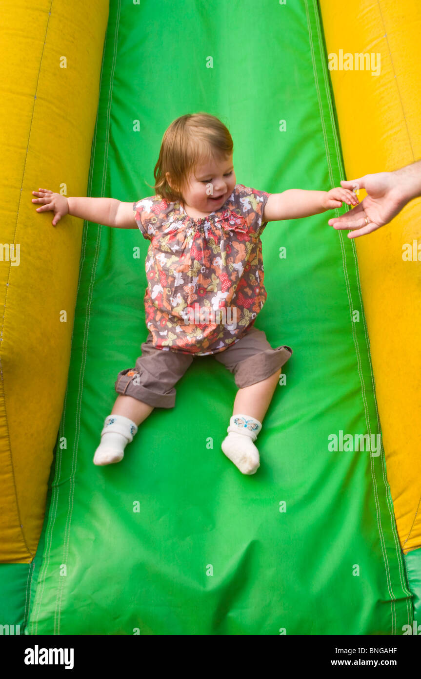 Vertical portrait of a little girl having great fun sliding down an ...