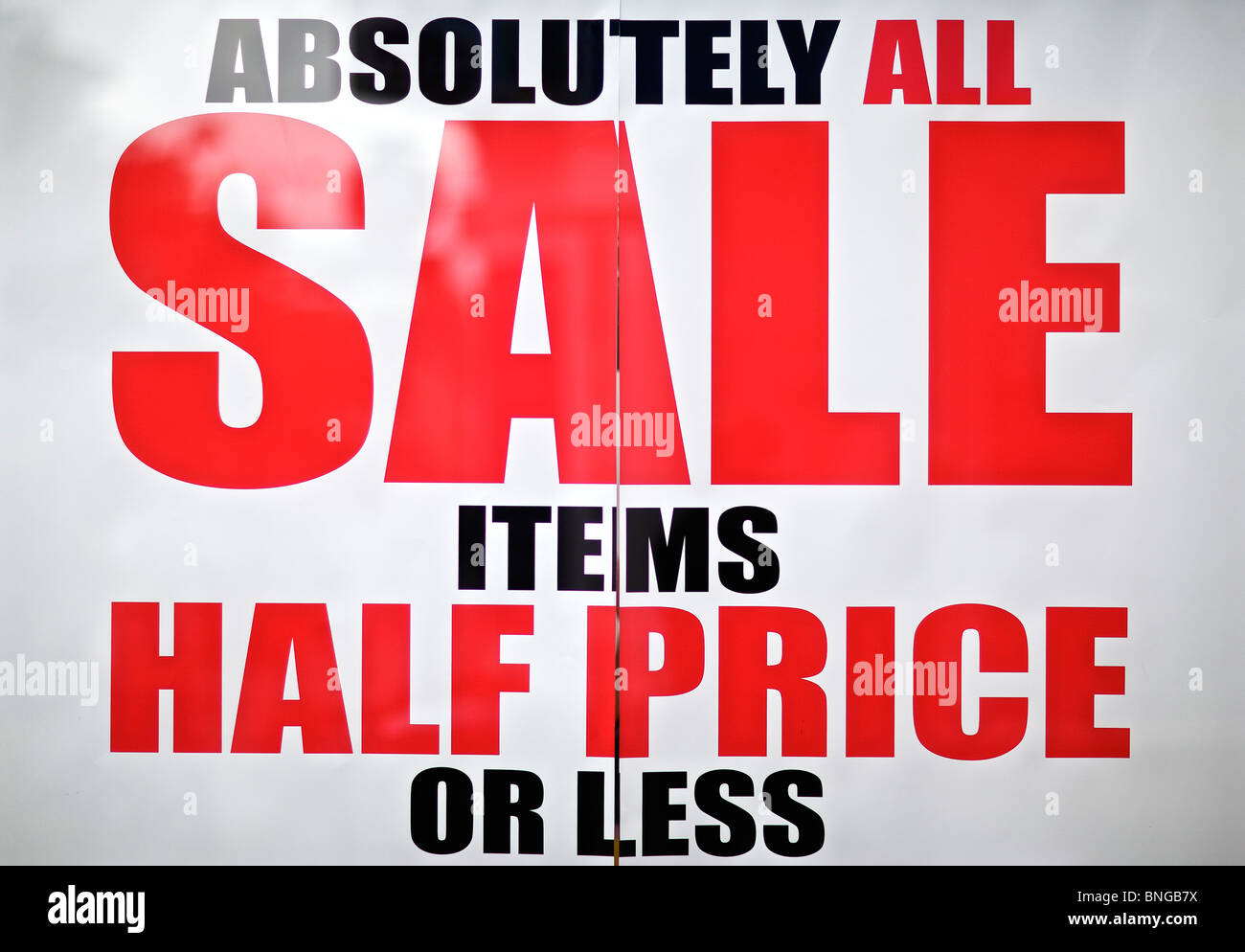 Half price sale poster in fashion shop window on High Street Stock Photo
