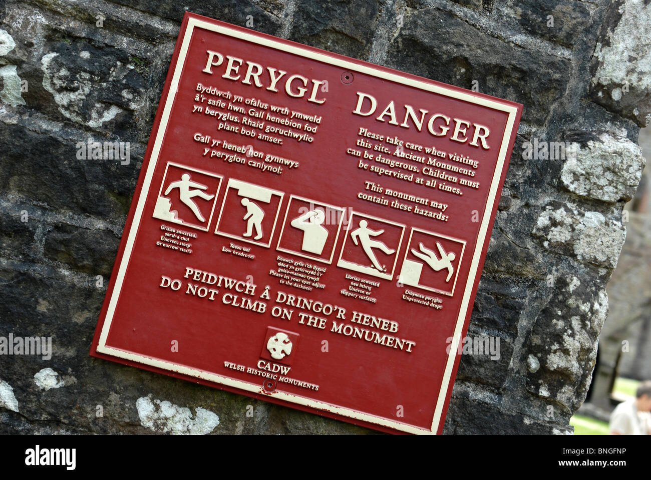 Public information sign warning of dangers at a historic monument in Wales Stock Photo