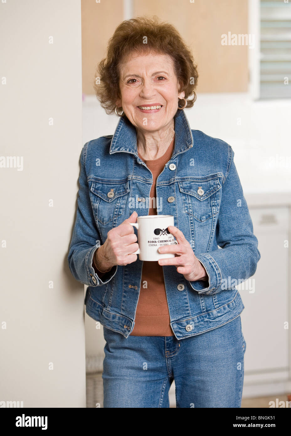 Senior woman standing in the kitchen and drinking coffee Stock Photo