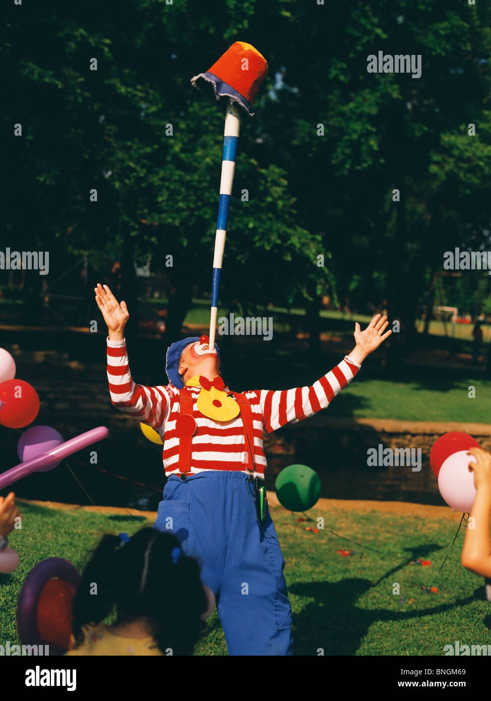 Clown performing a balancing trick with a pole and a bucket in a