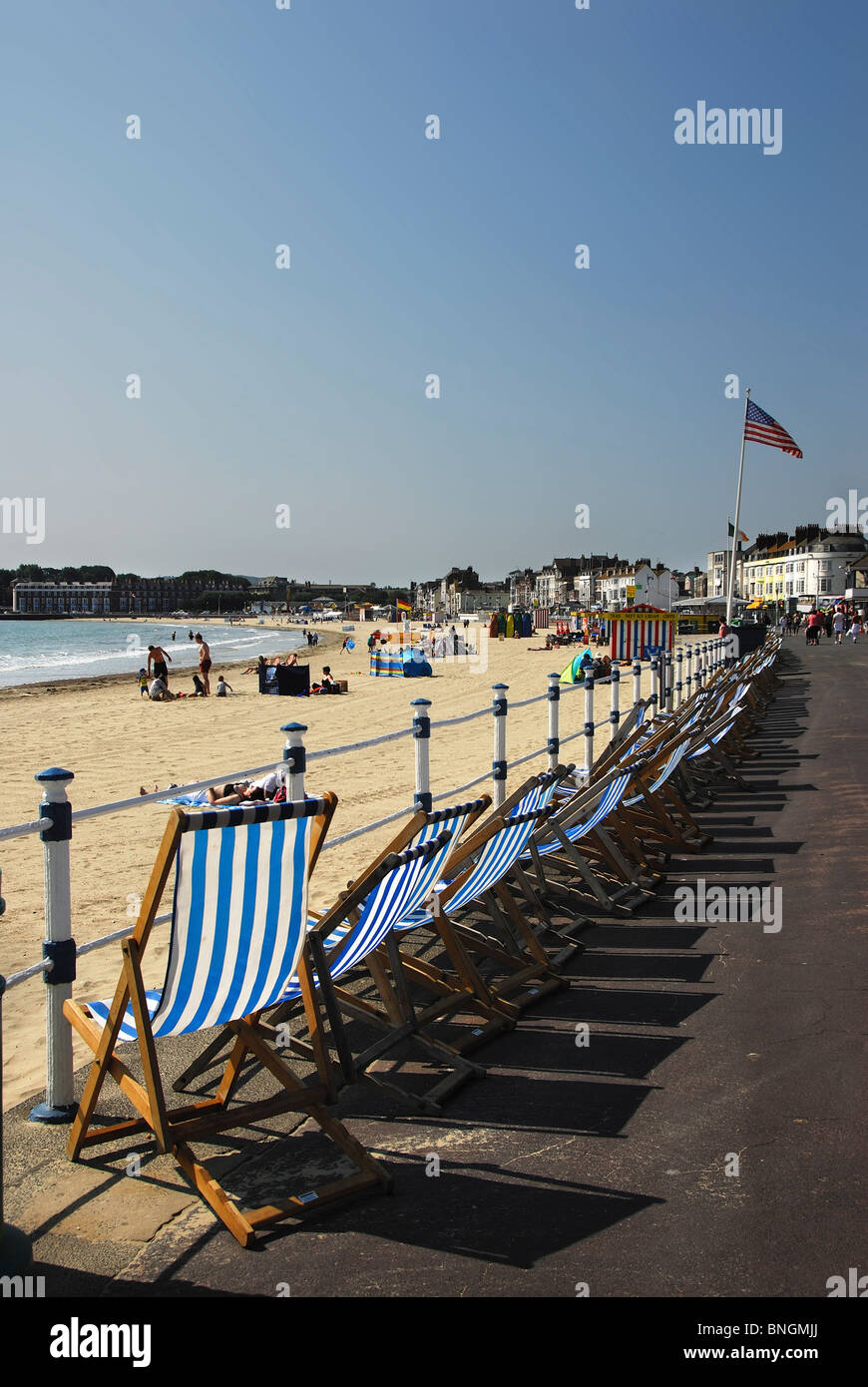 A row of empty deck chairs on Weymouth esplanade by the beach. Dorset