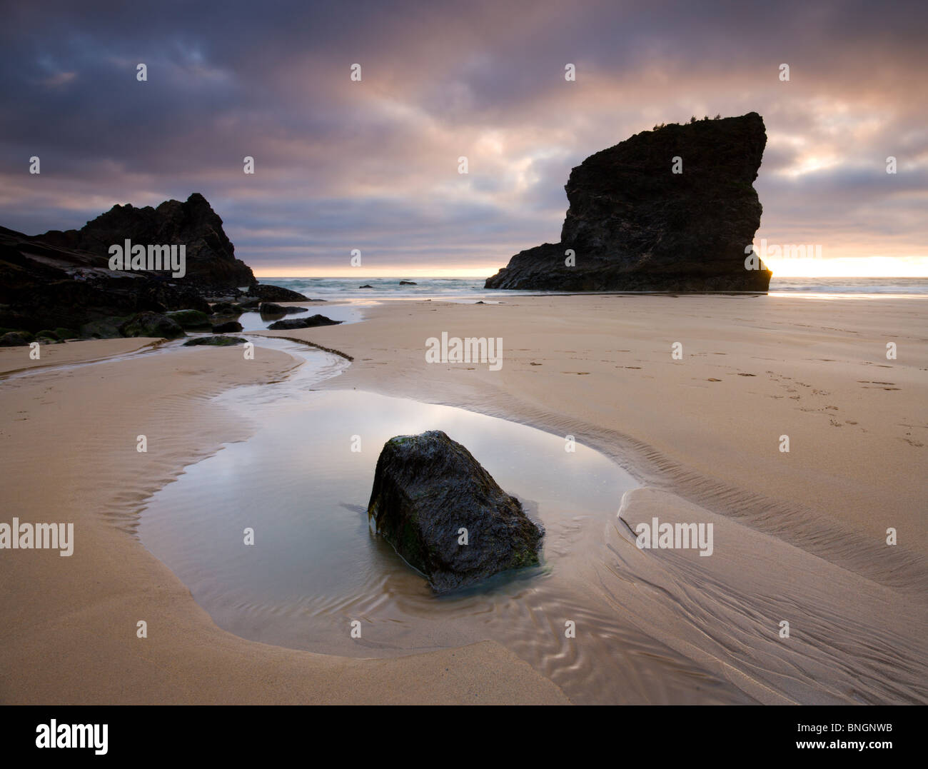 Rockpool and seastack on the sandy beach of Bedruthan Steps at sunset, Cornwall, England. Spring (May) 2009 Stock Photo