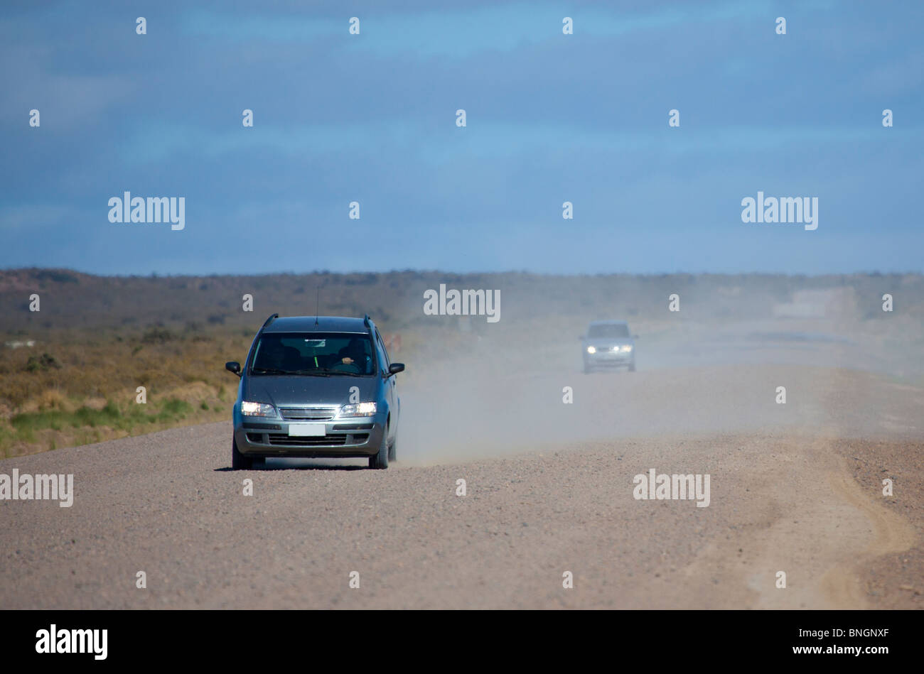 Cars driving towards the camera along a dusty gravel road Stock Photo
