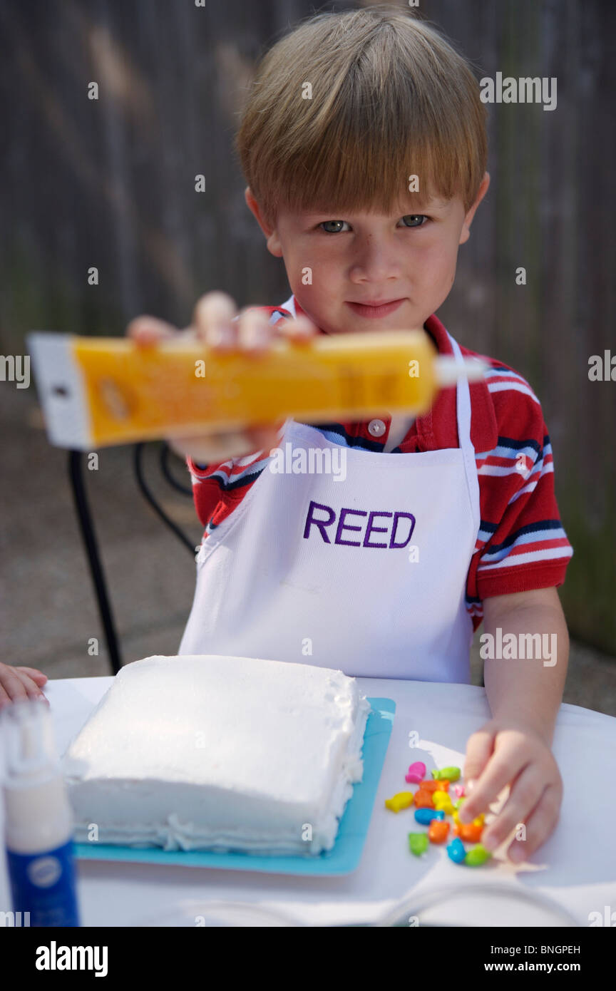 Young boy teaching how to put icing on cake Stock Photo Alamy