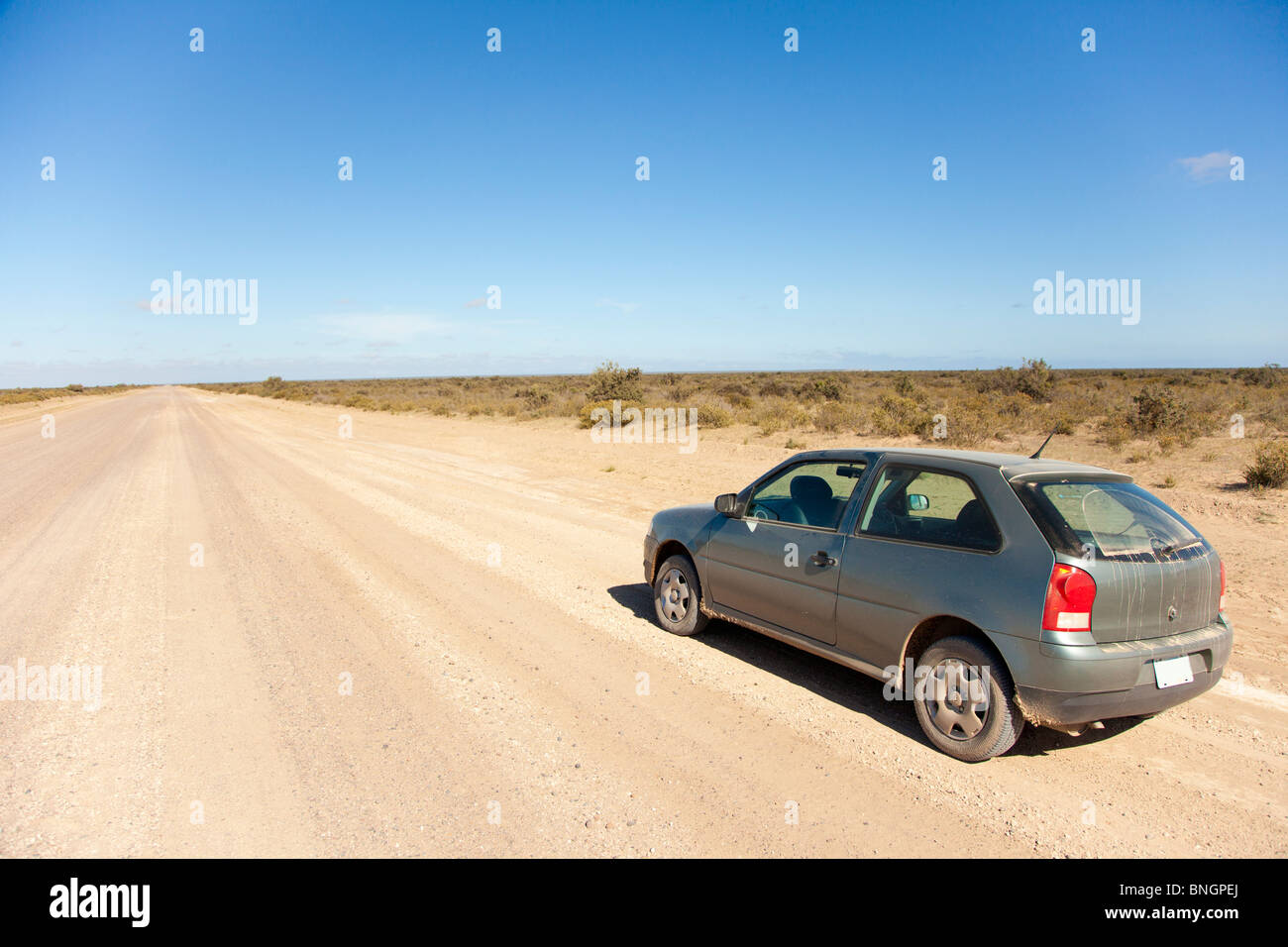 Car on the side of a long dirt road Stock Photo