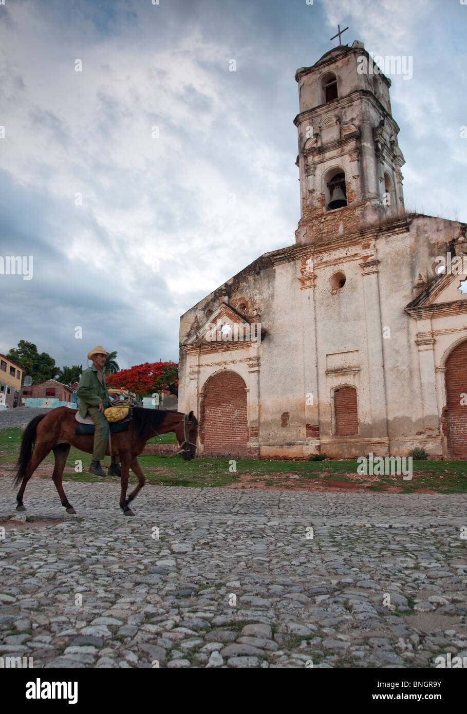 Trinidad local riding his donkey through the centre of town and past a church Stock Photo
