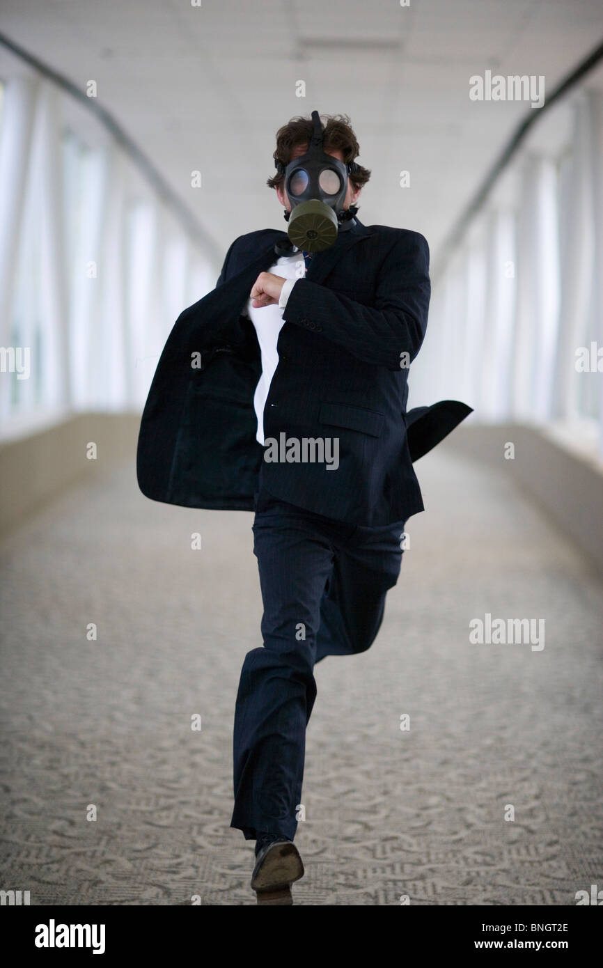 Businessman wearing gas mask running down corridor Stock Photo Alamy