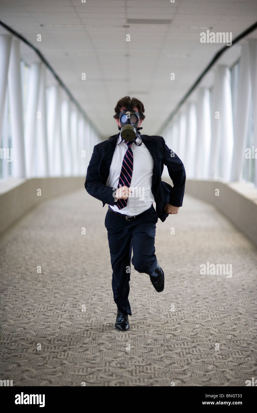 Businessman wearing gas mask running down corridor Stock Photo Alamy