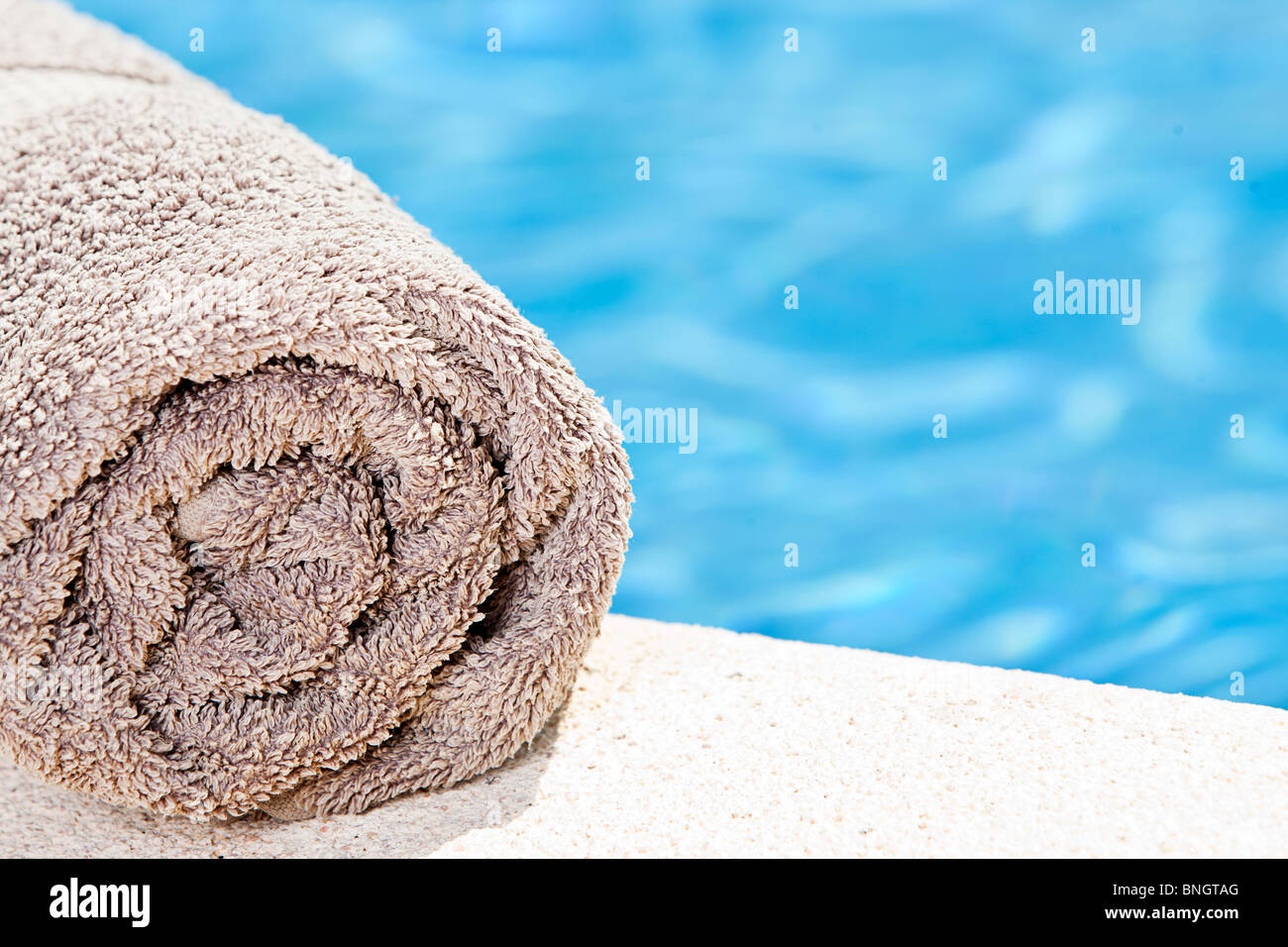 Shot of a Rolled Towel next to the Swimming Pool Stock Photo