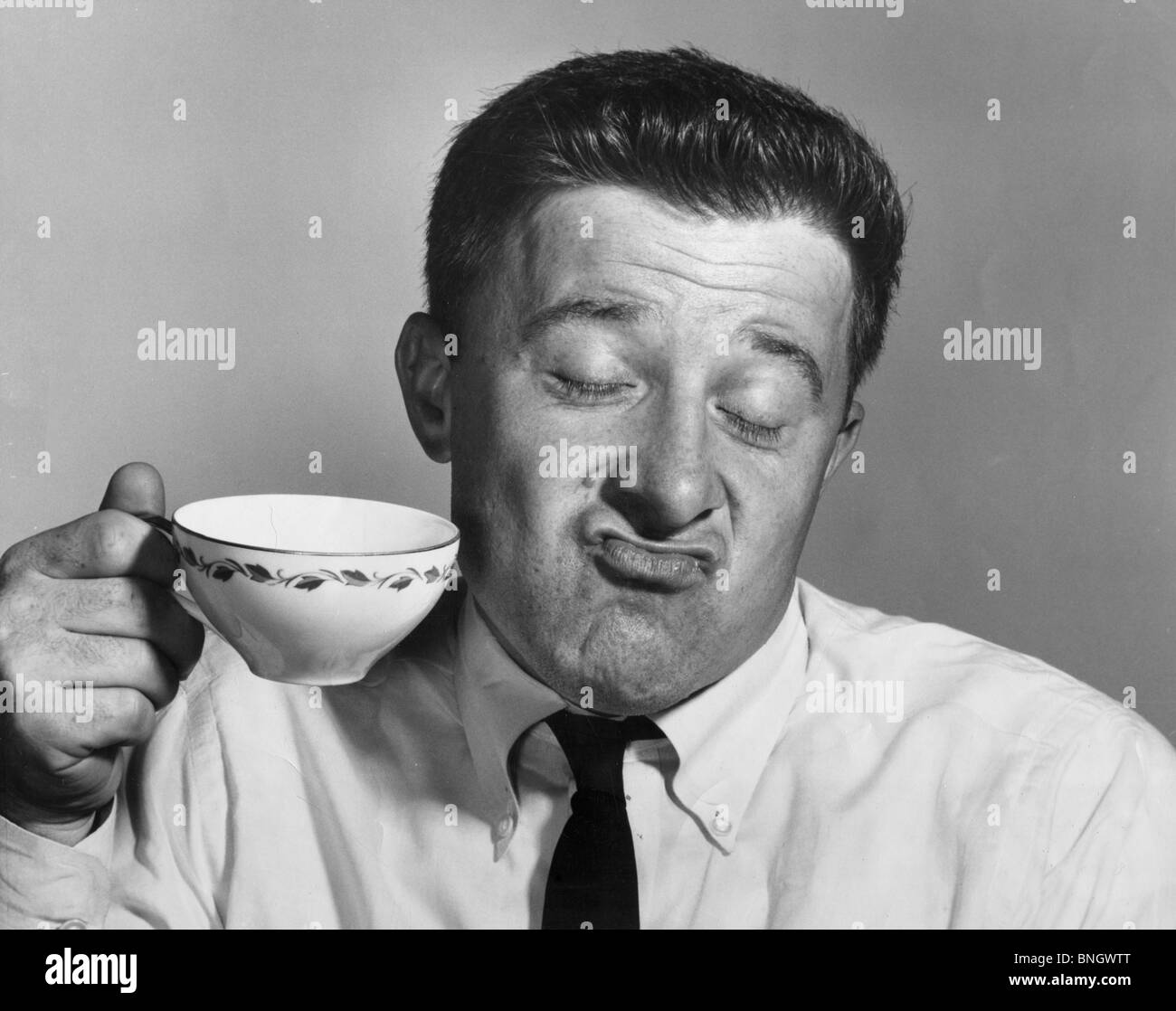 Mature man holding tea cup and making a face Stock Photo