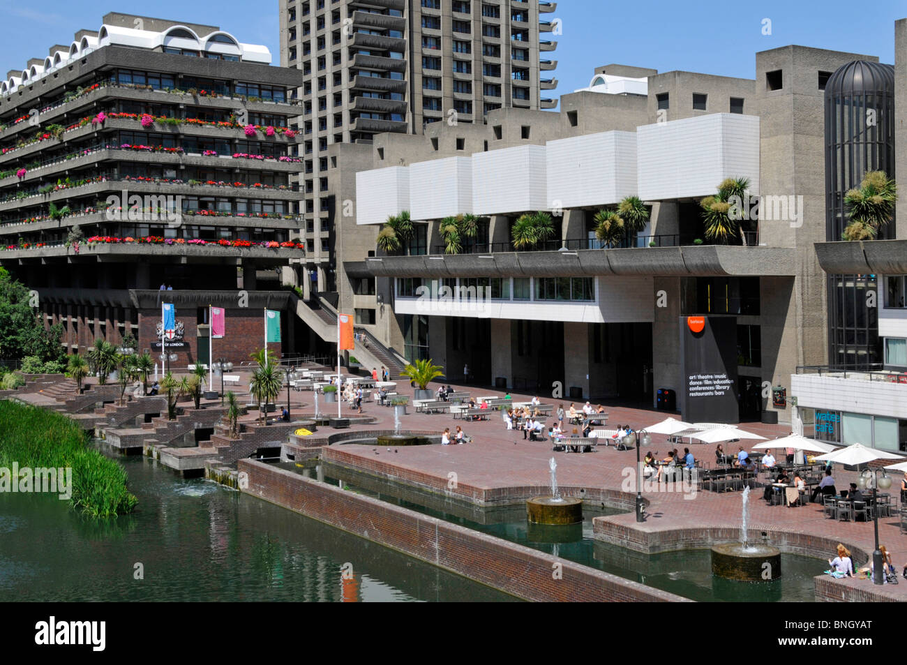 Lake & water feature fountains at urban Barbican Centre brutalist architecture high rise landmark skyscraper apartment homes City of London England UK Stock Photo