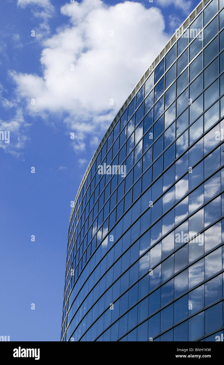 White clouds and a blue sky reflecting in the mirrored windows of a ...