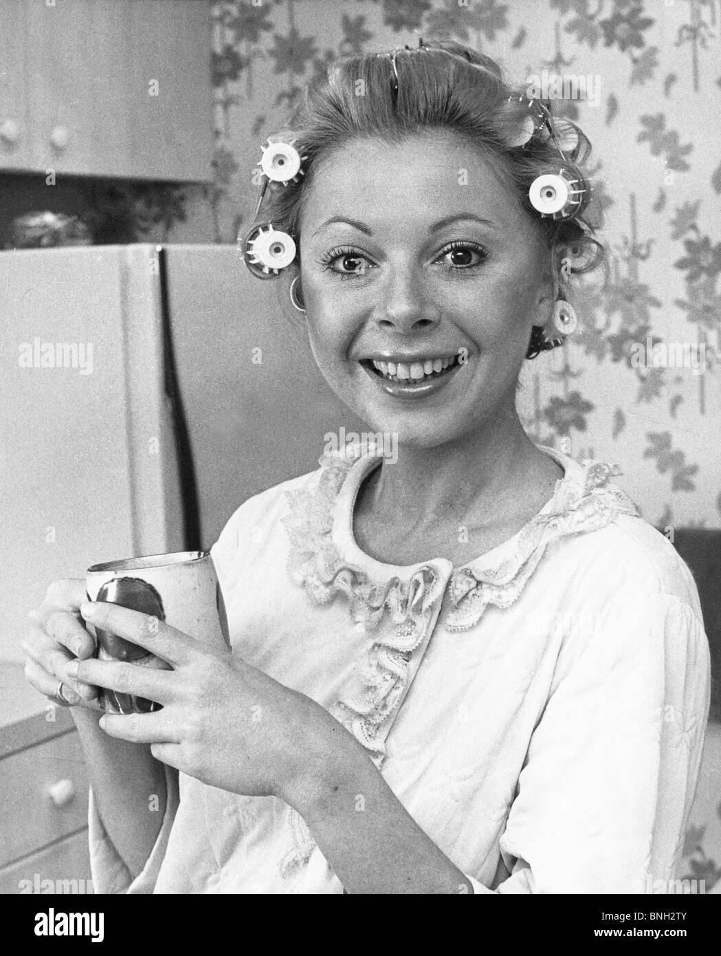 Portrait of a young woman with rollers holding a tea cup Stock Photo