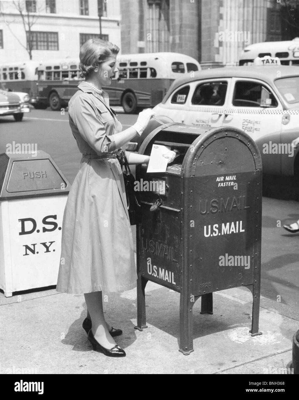Side profile of a mid adult woman dropping mail in a mailbox Stock Photo