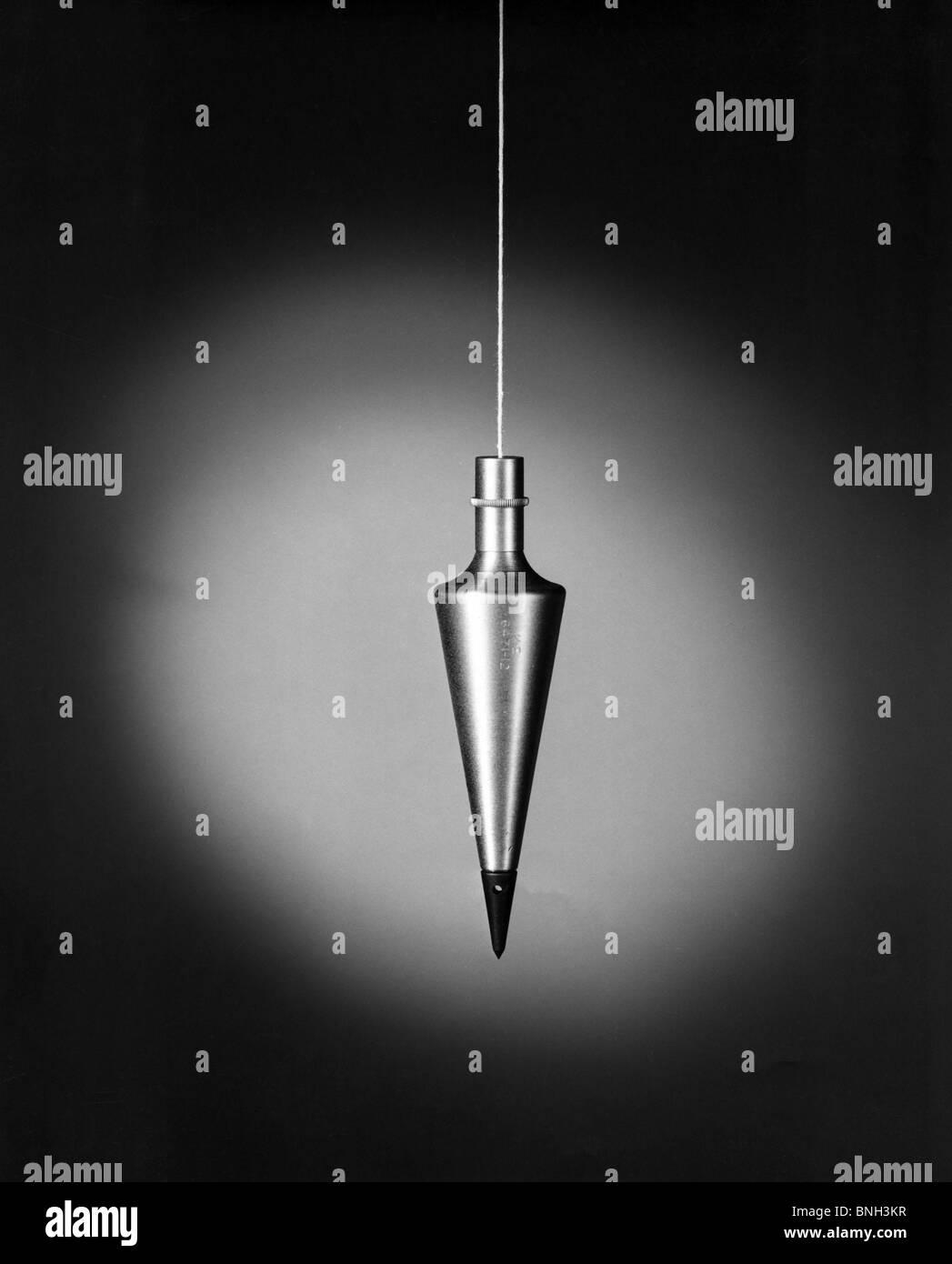 Plumb weight hanging on string Stock Photo