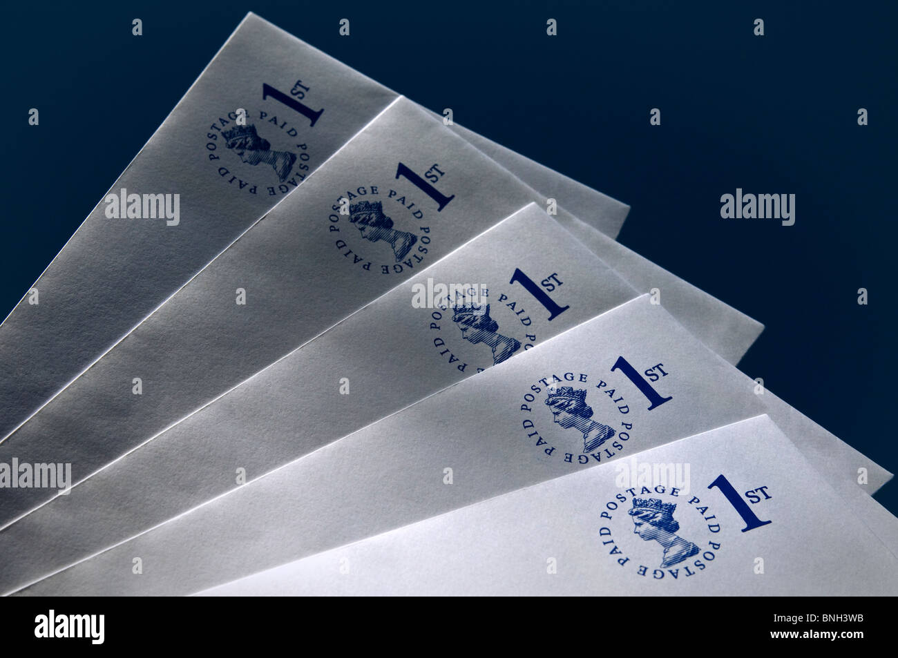 ENVELOPES Pre-paid UK first class envelopes on dark blue background with dappled shafts of sun Stock Photo
