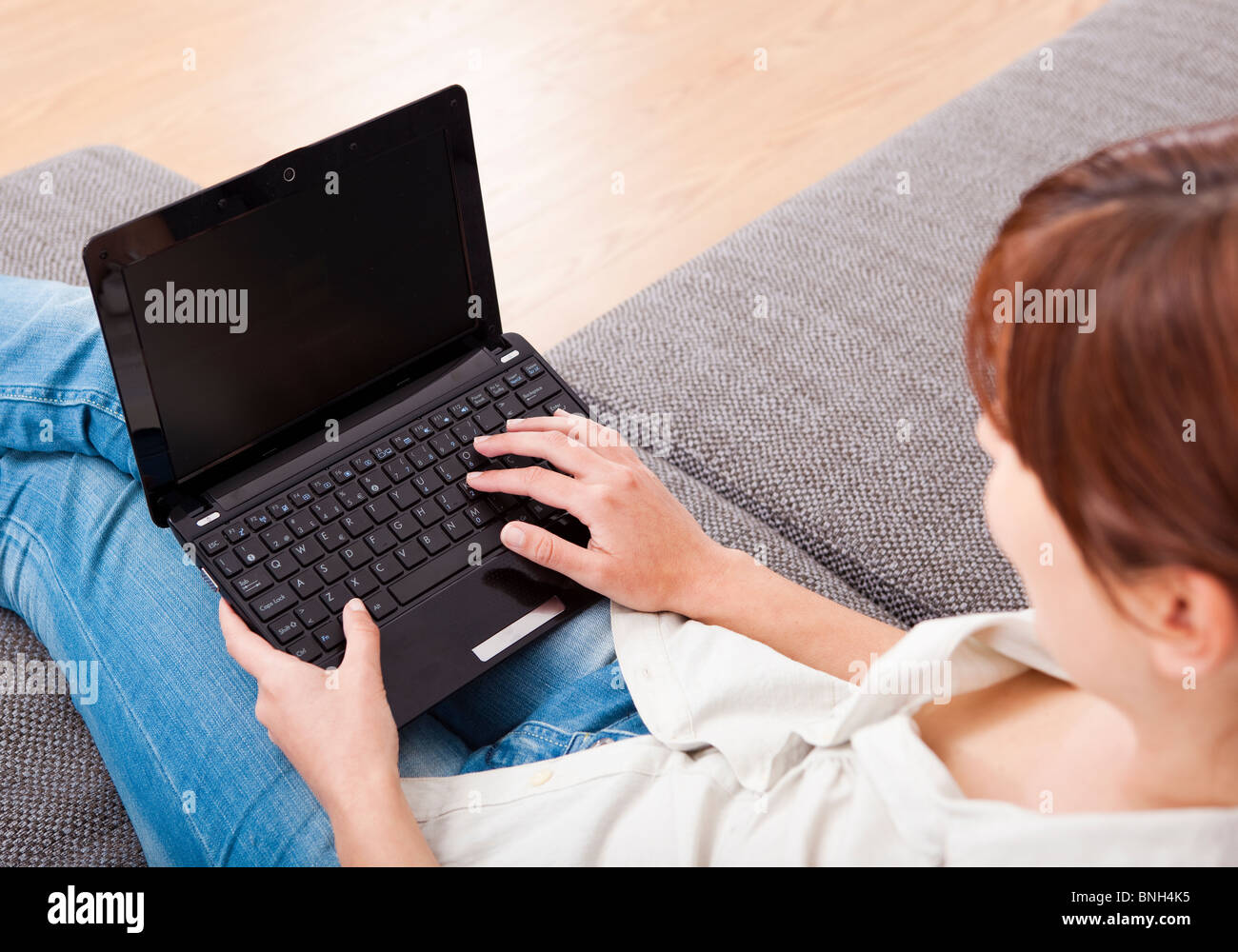 Young woman at home seated on sofa and working with a laptop Stock ...