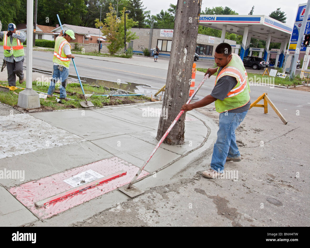 Workers install a curb ramp at a street intersection to allow access for people with
