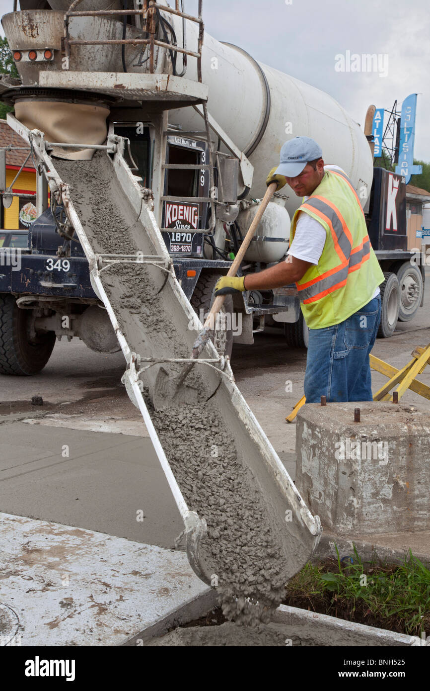 Workers install a curb ramp at a street intersection to allow access for people with disabilities. Stock Photo