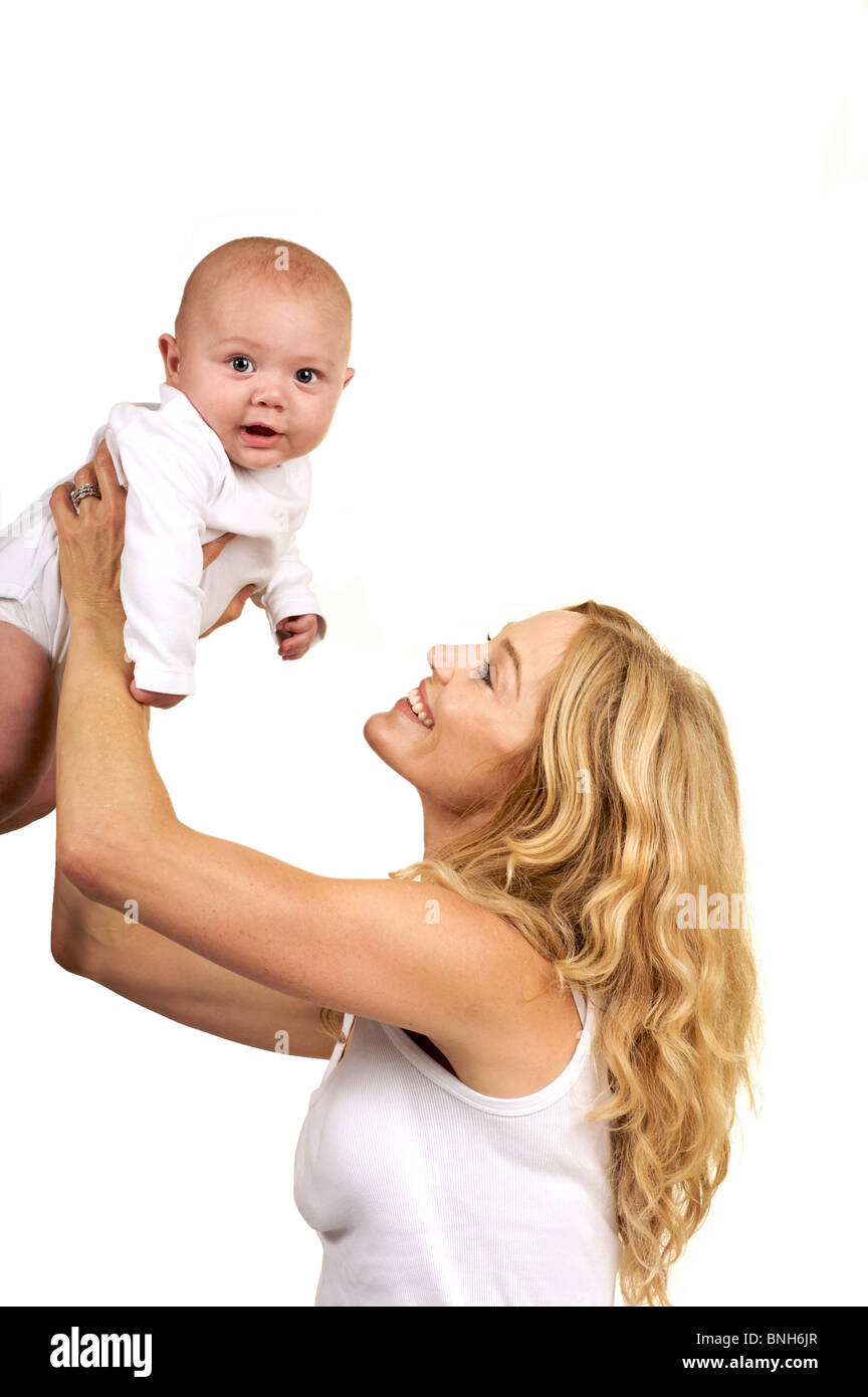 Mother holding up her little baby both dressed in white Stock Photo