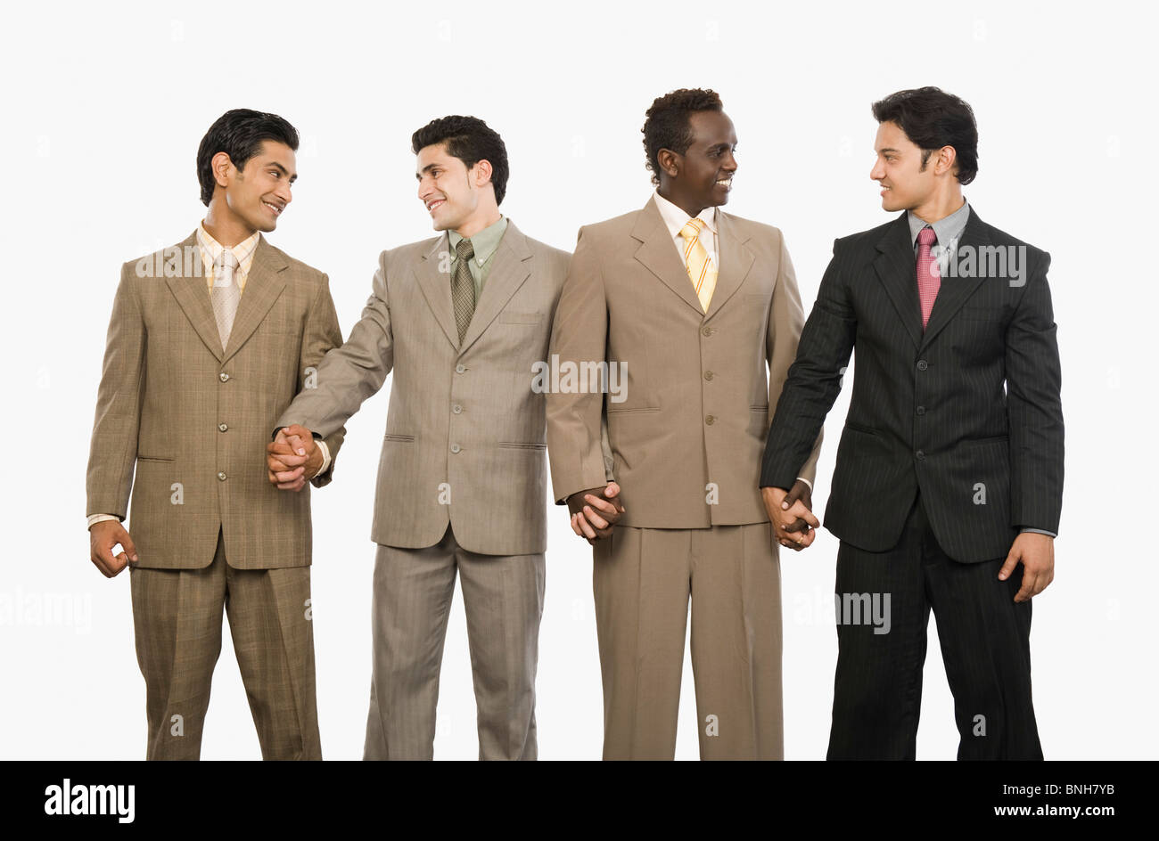 Four businessmen standing with holding hands Stock Photo