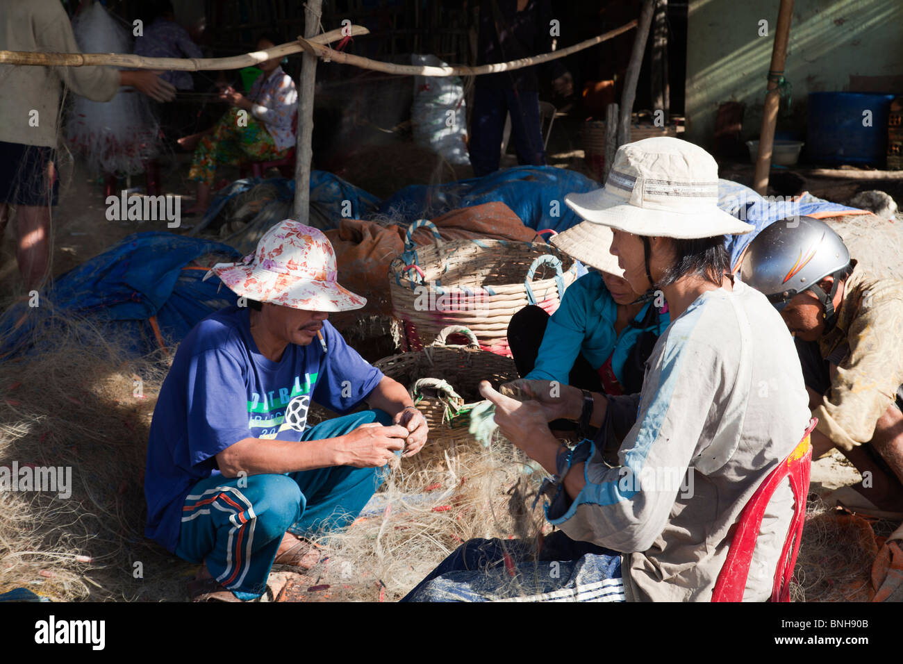 Vietnamese fishermen mending fishing nets Mui Ne on beach Stock Photo