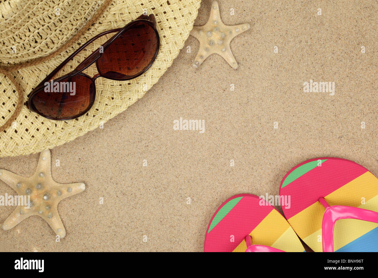 Colorful summer beachwear, flip flops, hat, sunglasses and starfish on sand beach. Stock Photo