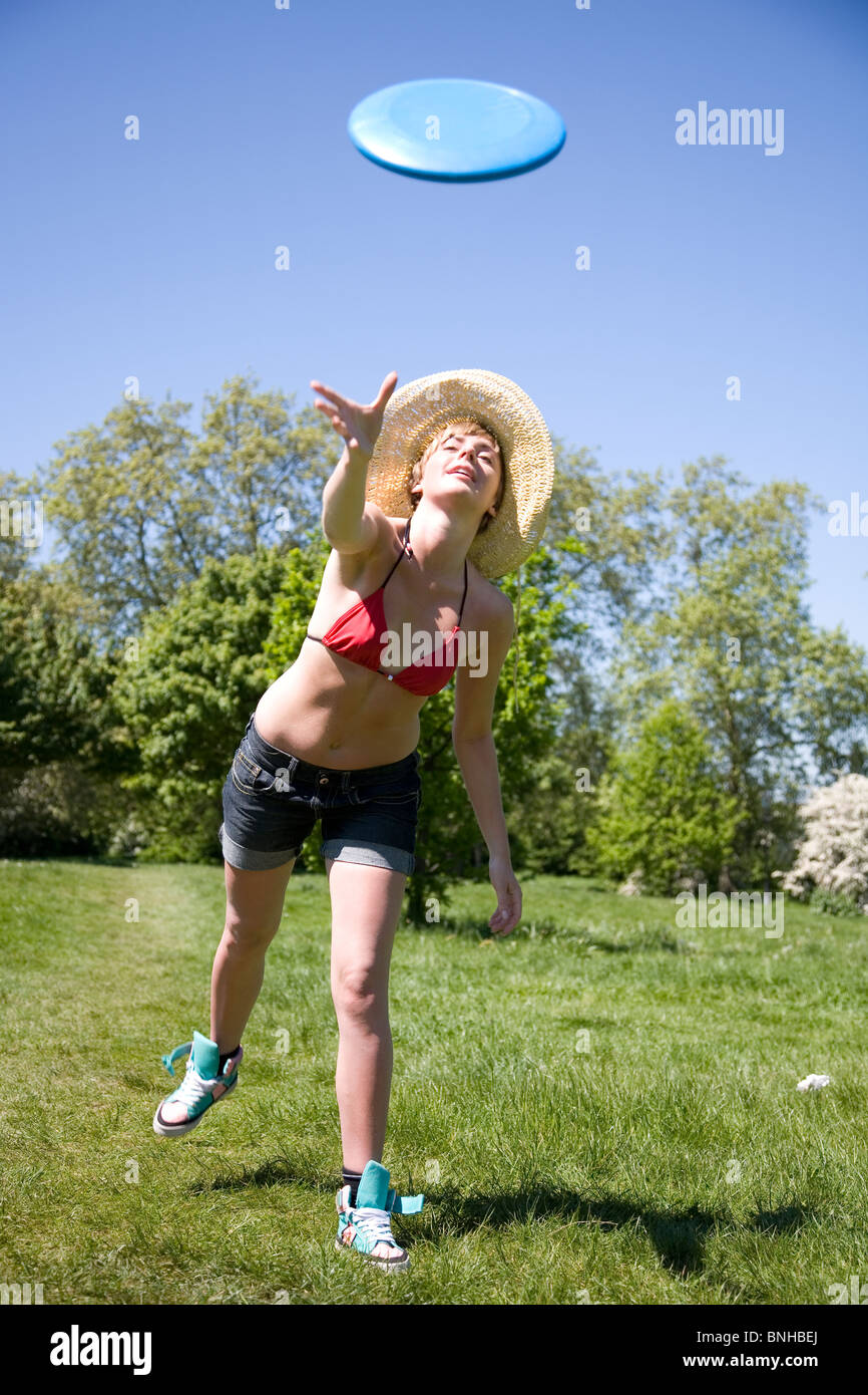 Young woman with straw hat playing Frisbee in the park Stock Photo