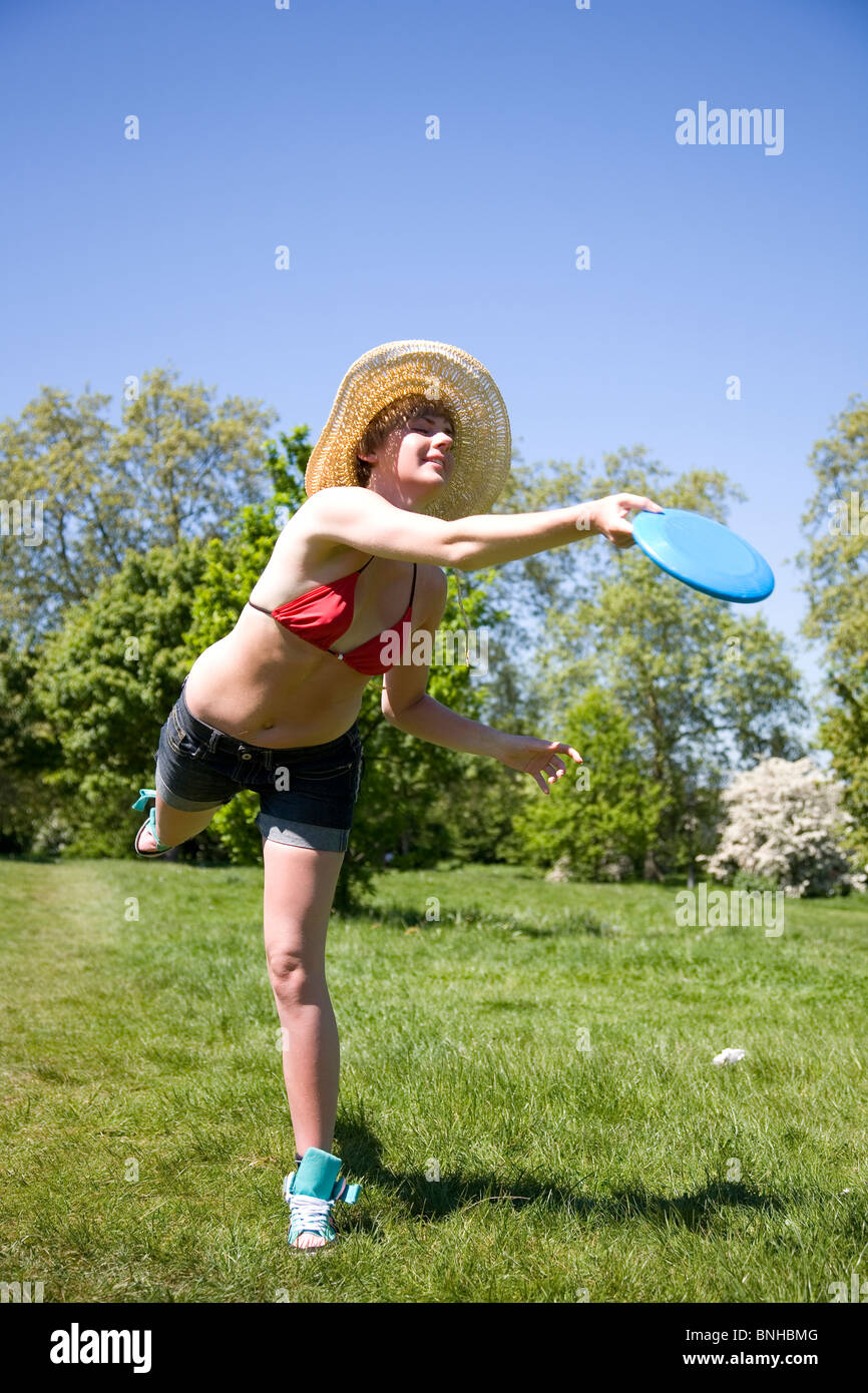Young woman with straw hat playing Frisbee in the park Stock Photo