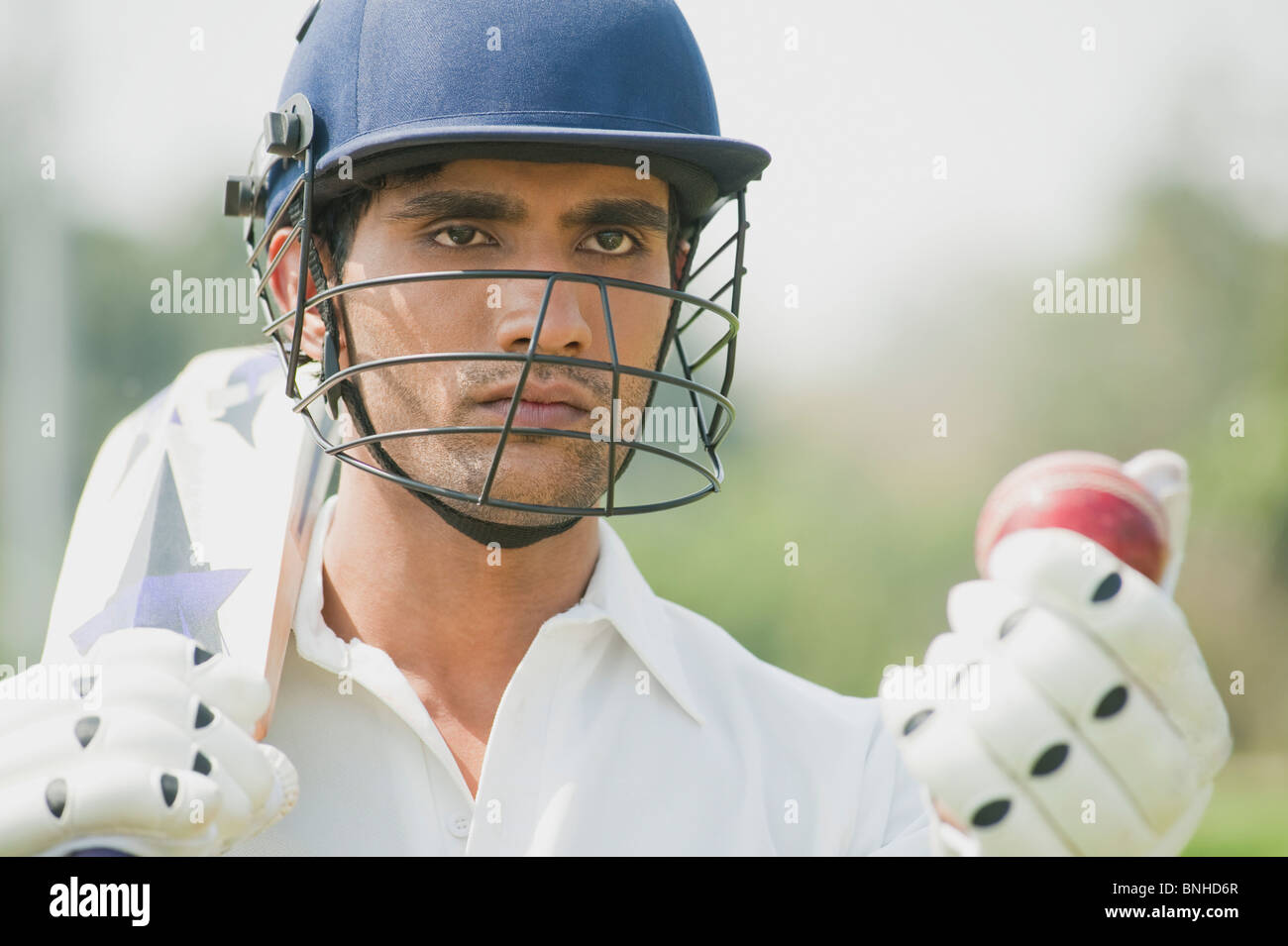 Cricket batsman holding a cricket bat with a cricket ball Stock Photo