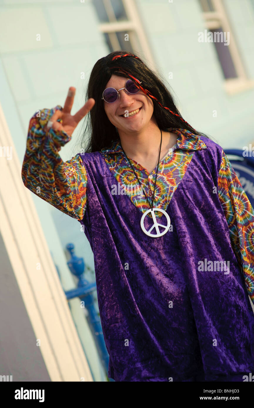 A man giving peace sign dressed up as a hippy for a 1970's decade themed birthday party, UK Stock Photo