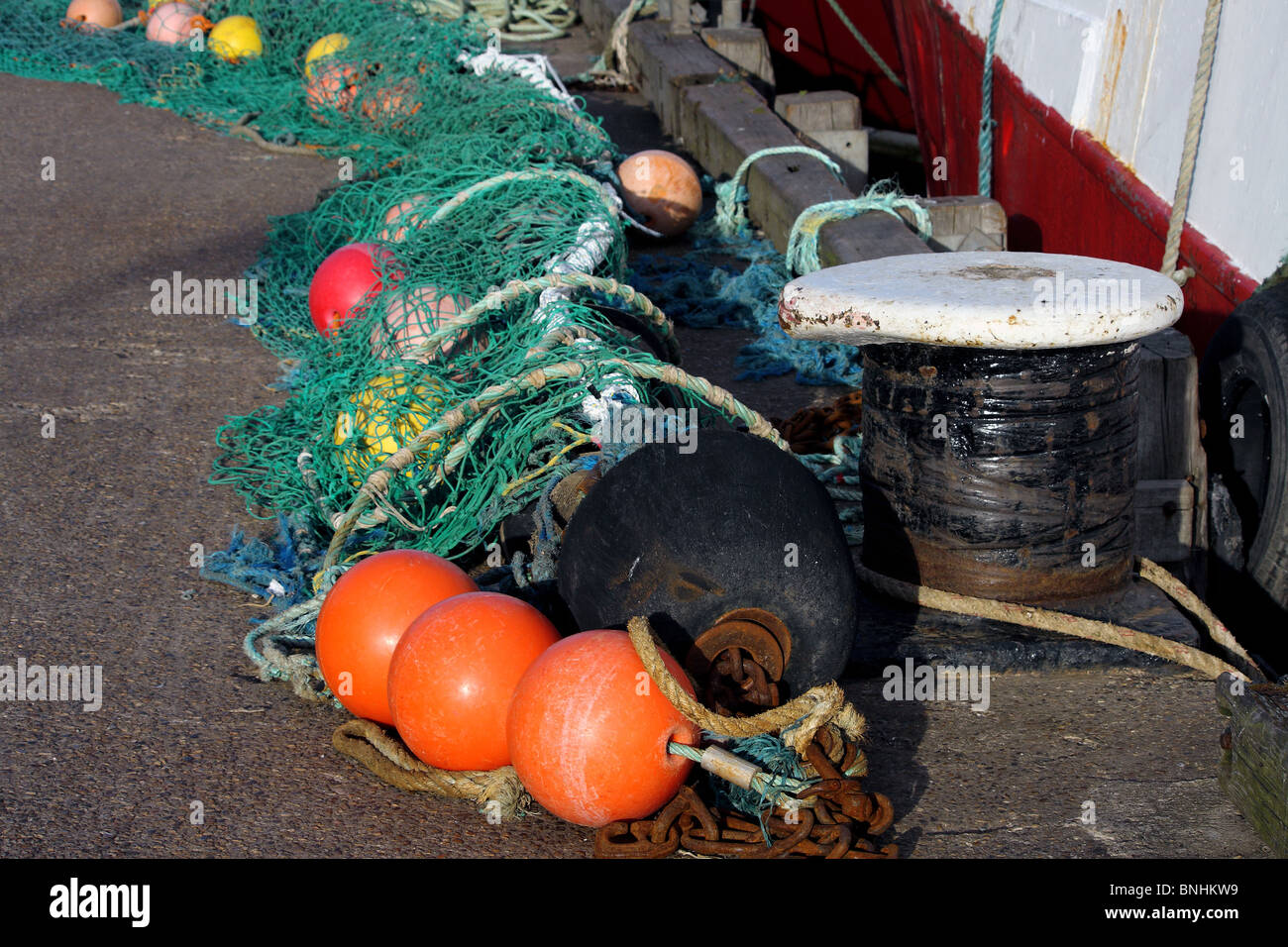 A sea fishing net cast aside on the pathway beside the fishing boat Stock Photo