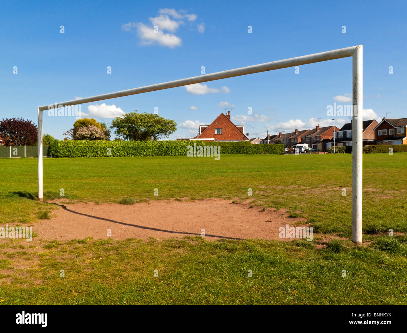 Goal posts on a football or soccer pitch in a suburban park with houses behind Stock Photo